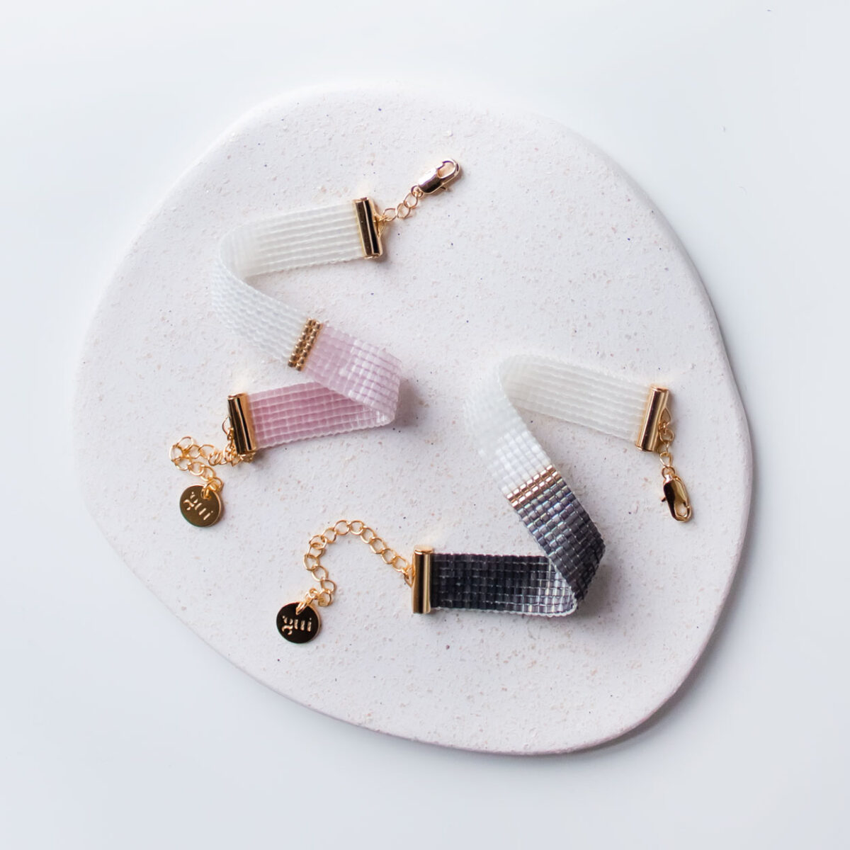 Elegant black and pink bracelets and necklaces displayed on a white ceramic plate.