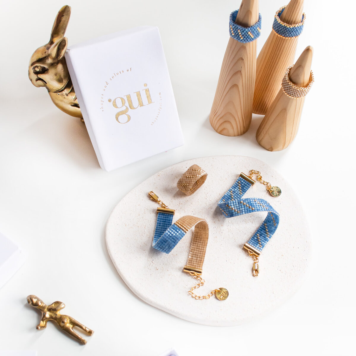 Elegant jewelry pieces displayed on a marble plate with Gui branded packaging around.